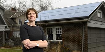 Assistant professor Andrea La Nauze posing in front of roof lined with solar panels