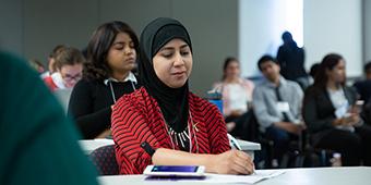 student wearing headscarf taking notes in class